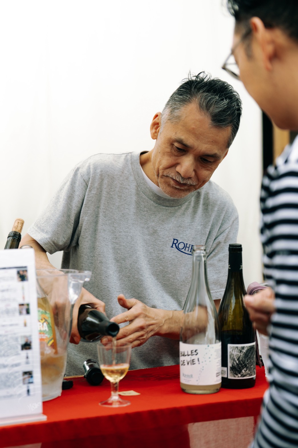 ワインを注ぎながら来場者と会話する出店者